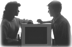 Fotografa mostrando a un hombre frente a una mujer con una computadora de por medio.