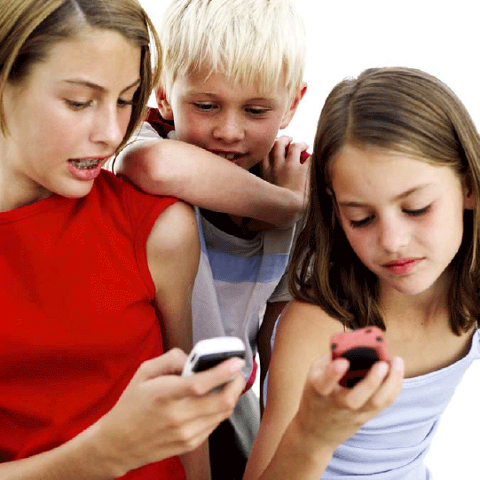 Photograph showing two girls using cell phones with a boy looking over their shoulders