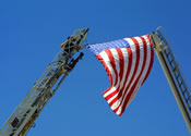photograph of two fire truck ladders, one with an American flag
