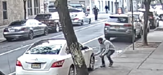 Picture of the defendant retrieving a gun from under a car