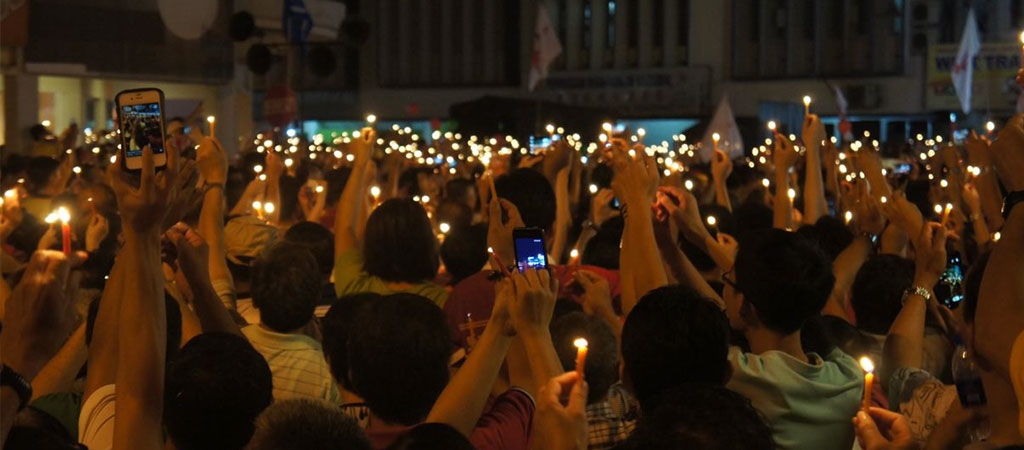 An image of community members holding a candlelight vigil