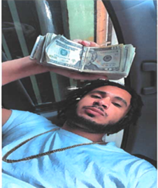 Defendant taking selfie holding up wad of cash in his hand