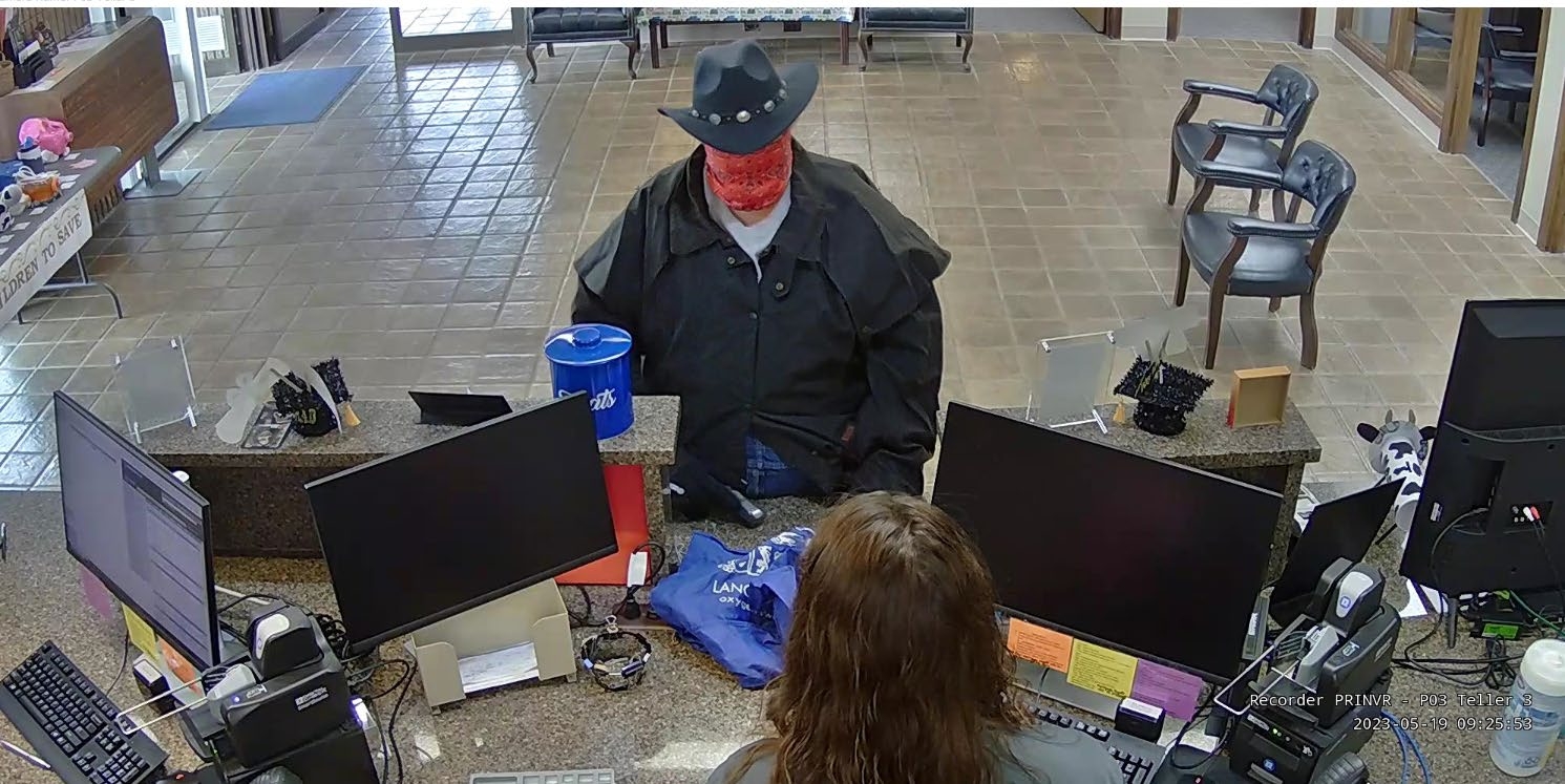 Blink points a firearm at the bank clerk during the armed robbery of First Interstate Bank.