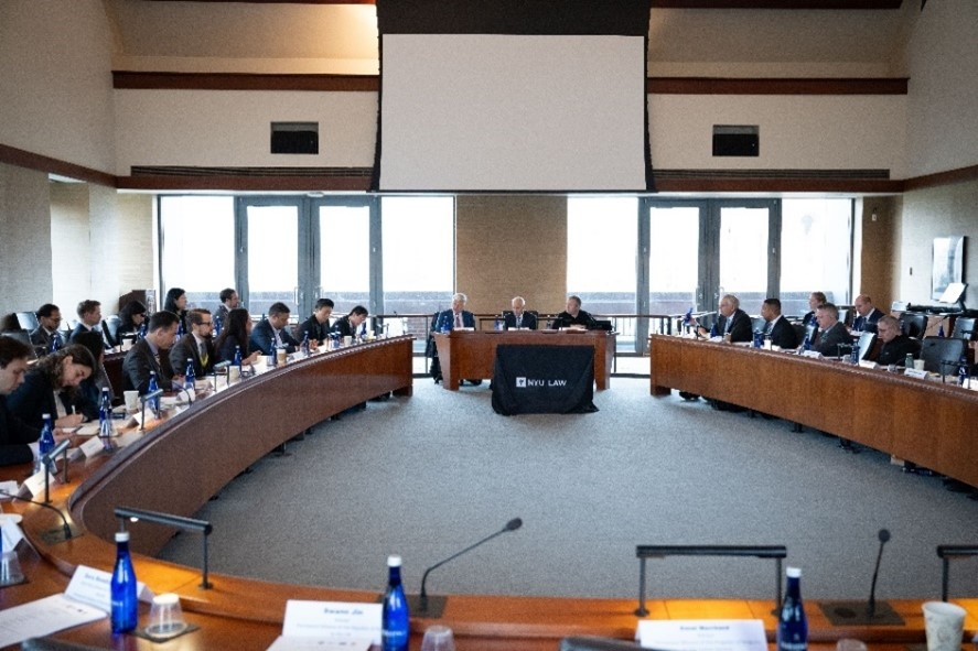 Group of people sitting in a room with desks.