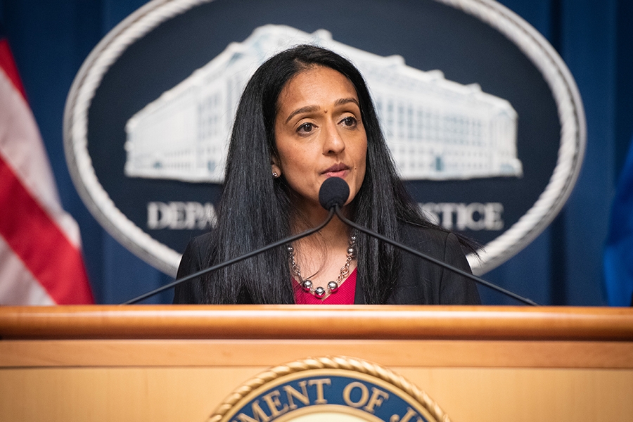 Associate Attorney General Vanita Gupta speaks from the podium. The Department of Justice seal is behind her, and an American flag can be seen on the left.