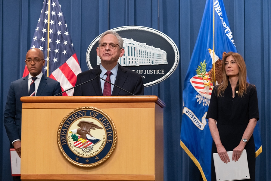 Merrick B. Garland speaks at the podium. To the left is U.S. Attorney for the southern district of New York Damian Williams, and to the right is DEA Administrator Anne Milgram. An American flag, the Department of Justice seal, and the Department of Justice flag are seen in the background.