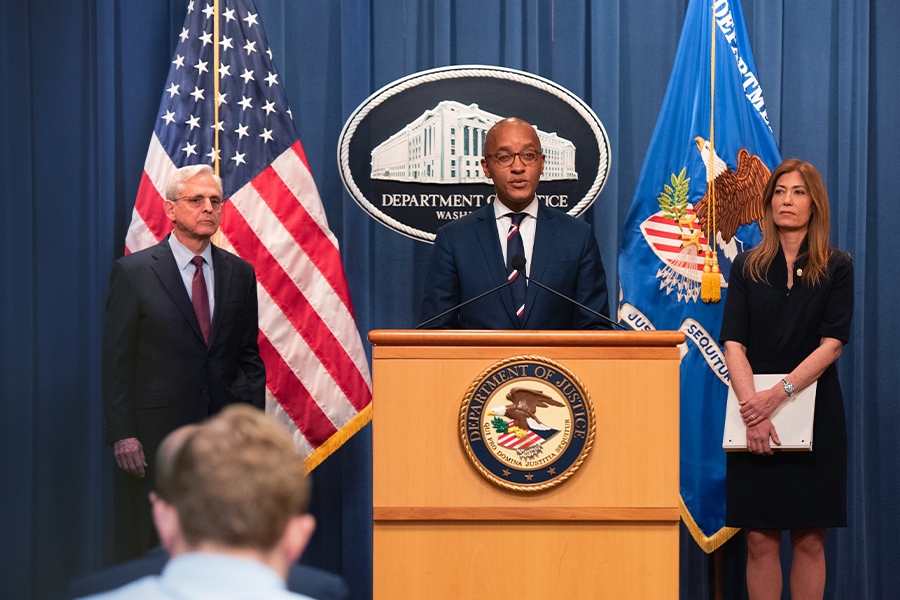 U.S. Attorney for the Southern District of New York Damian Williams speaks at the podium. To the left is Attorney General Merrick B. Garland, and to the right is DEA Administrator Anne Milgram. An American flag, the Department of Justice seal, and the Department of Justice flag are seen in the background.