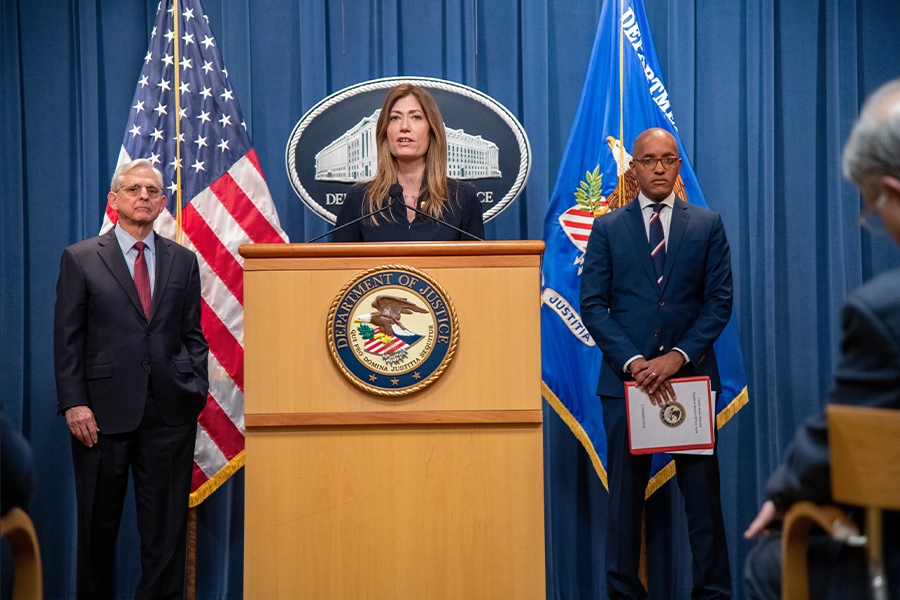 DEA Administrator Anne Milgram speaks at the podium. To the left is Attorney General Merrick B. Garland, and to the right is U.S. Attorney for the southern district of New York Damian Williams. An American flag, the Department of Justice seal, and the Department of Justice flag are seen in the background.