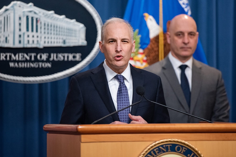 Assistant Attorney General Matthew G. Olsen speaks at a podium bearing the Department of Justice seal. To the right is Assistant Director Alan E. Kohler Jr. of the FBI's Counterintelligence Division.