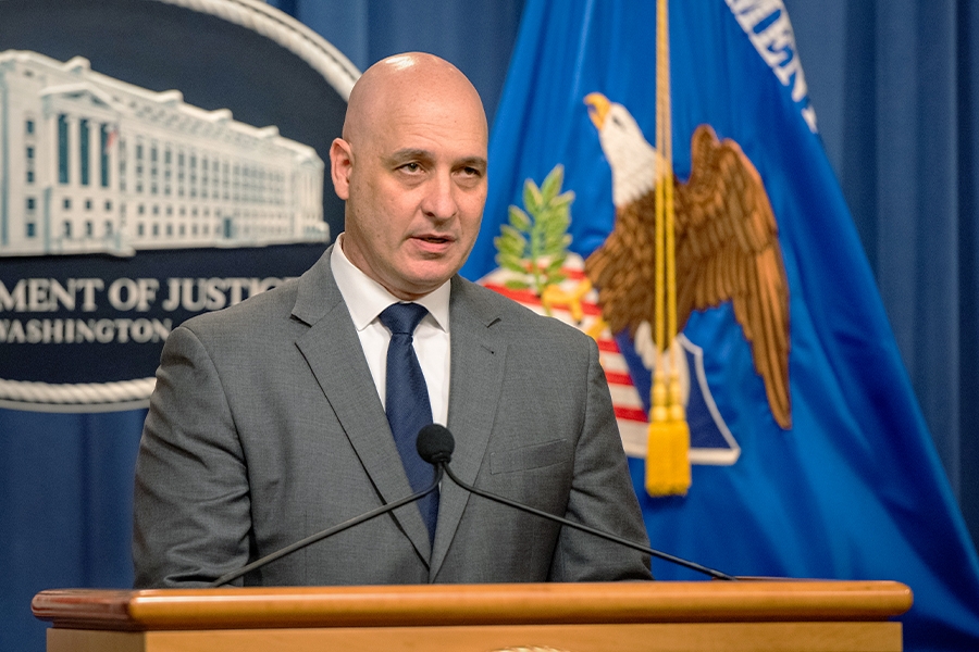 Assistant Director Alan E. Kohler Jr. of the FBI's Counterintelligence Division speaks at a podium. The Department of Justice seal and flag are seen the background.