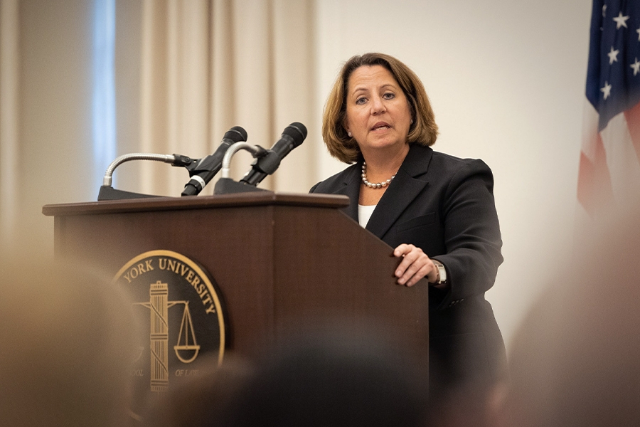 Deputy Attorney General Lisa O. Monaco speaks to an audience of officials and attorneys at a podium bearing the New York University seal.