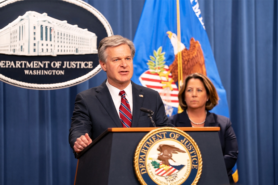 FBI Director Christopher Wray delivers remarks at a podium bearing the Department of Justice seal.