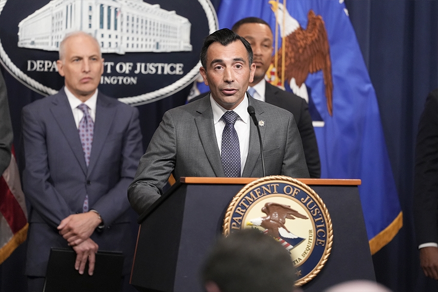 U.S. Attorney Martin Estrada for the Central District of California delivers remarks from a podium bearing the Department of Justice seal