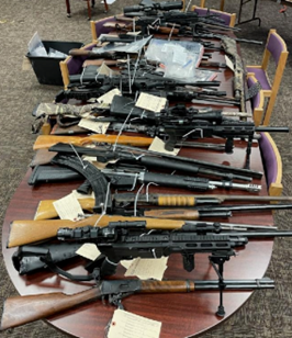 Guns laying on a table that have been tagged by law enforcement 