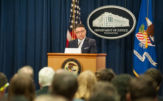 Makan Delrahim speaking at a podium in front of an audience of event attendees.