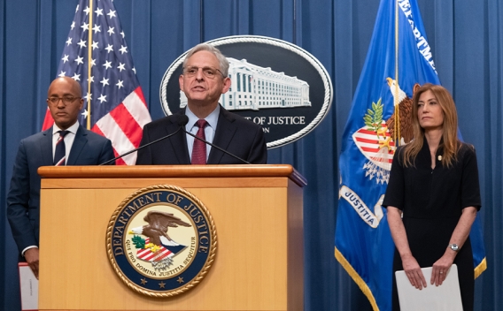 Merrick B. Garland speaks at the podium. To the left is U.S. Attorney for the southern district of New York Damian Williams, and to the right is DEA Administrator Anne Milgram. An American flag, the Department of Justice seal, and the Department of Justice flag are seen in the background.