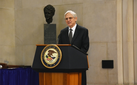 Attorney General Merrick B. Garland speaks at a podium bearing the Department of Justice seal.