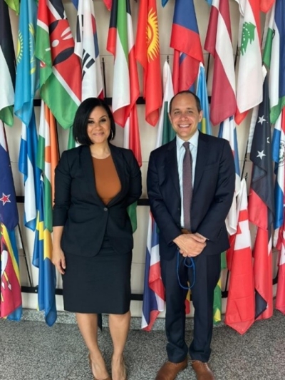Office for Access to Justice Director Rachel Rossi and Senior Advisor Jesse Bernstein standing in front of national flags at the UN Crime Commission in Vienna