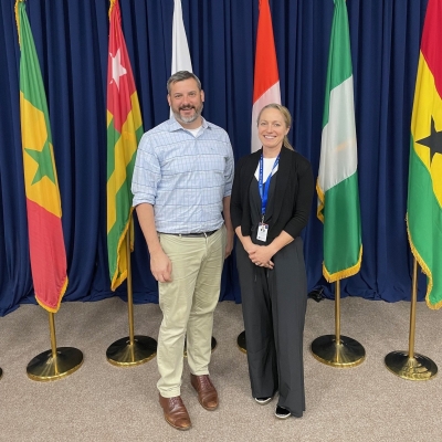 Two Justice Department personnel stand in front of flags from African nations