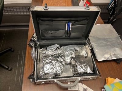 Three hand guns and ammo wrapped in foil, inside open metal briefcase.