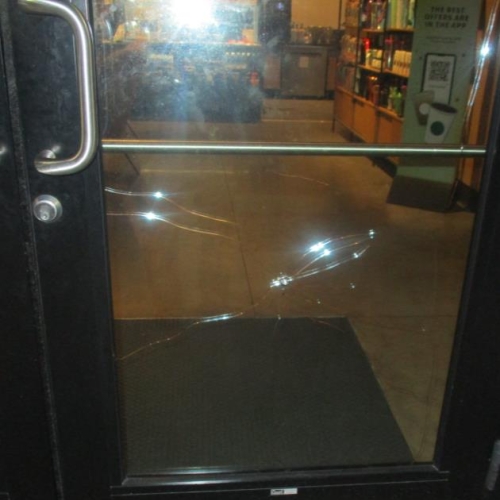 Photo of a glass door with large crack contained in the lower half of the glass