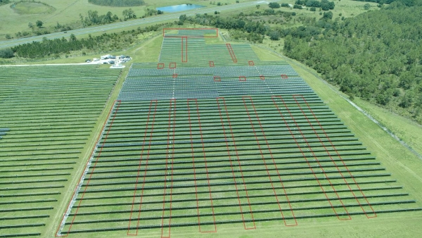 Photo of field lined with trees on the right side and multiple computer generated red rectangle outlines over parts of field