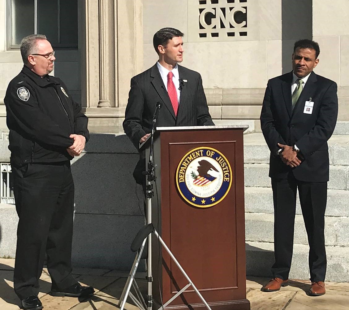 Image of U.S. Attorney Matt Martin speaking to the press with Greensboro Police Chief Wayne Scott and Dr. Tony Watlington of Guilford County Schools