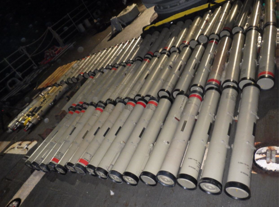 Array of missiles spread across the floor of an indoor facility.