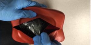 A red plastic oil container that contained the fentanyl pills. Dana had cut the bottom portion of the container along the seam to create a small opening where he inserted the drugs.