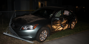 A car smashed up on a chain link fence 